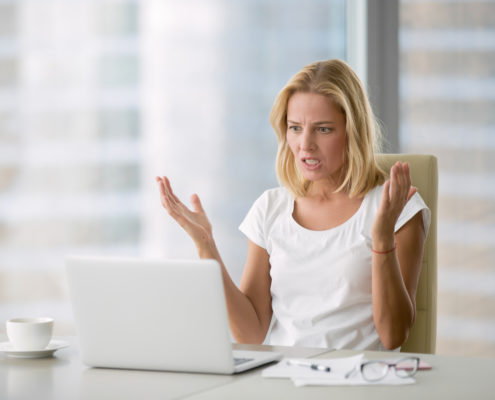 Woman at laptop hands up in frustration over doing social media herself