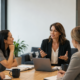 cmo | Lucé Media Five professionals sit around a wooden conference table in a modern office a woman in a black blazer speaks with a laptop and notes present nearby for discussion