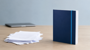 Quality Over Quantity in Blogging: Thin Drafts vs. Complete Content | Lucé Media | Lucé Media Messy stack of thin blog drafts beside one complete bound document illustrating quality over quantity in blogging