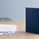 Quality Over Quantity in Blogging: Thin Drafts vs. Complete Content | Lucé Media Messy stack of thin blog drafts beside one complete bound document illustrating quality over quantity in blogging